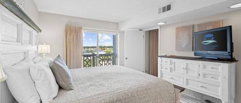 A bedroom with a bed, a TV, a dresser, and a balcony with a view.