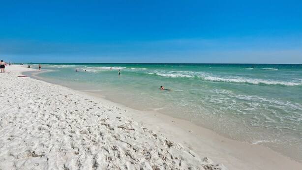Een strand met helderblauw water en een zandstrand.