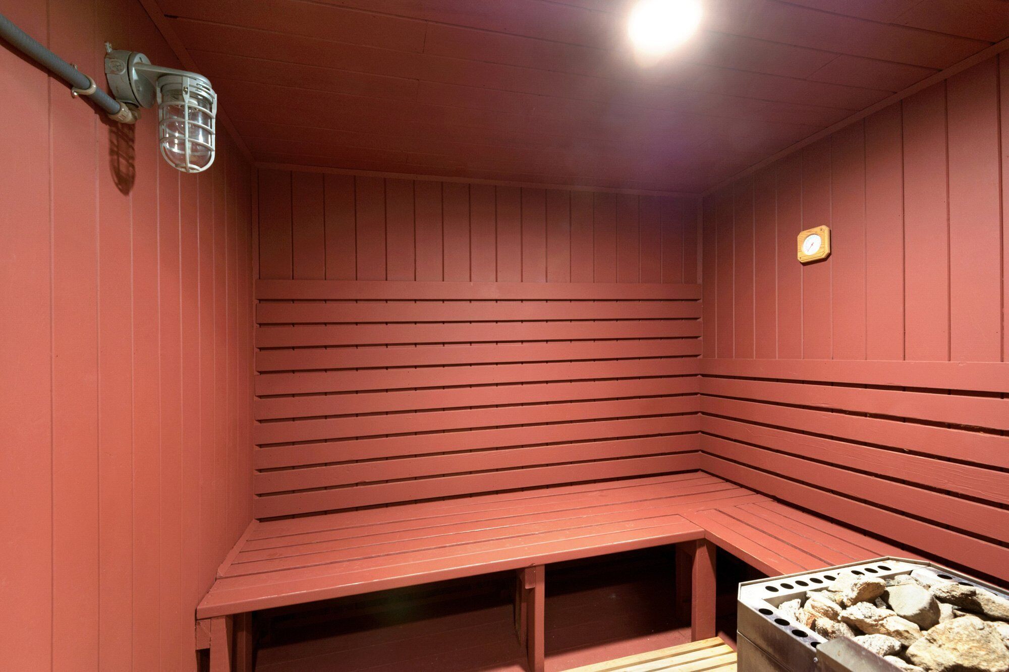 A sauna room with wooden benches and a stone heater.