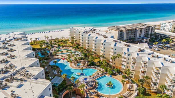 Un resort con varias piscinas, una playa y vista al océano.