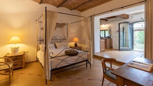 Een hemelbed met gordijnen, een houten tafel, een stoel, een nachtkastje en een lamp.