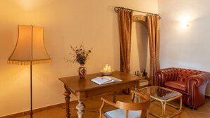 Een kamer met een houten tafel, een glazen salontafel, een leren bank, een lamp en een spiegel.