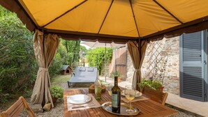 Een terras met een tafel gedekt voor twee personen, een fles wijn en een wijnglas op een dienblad.