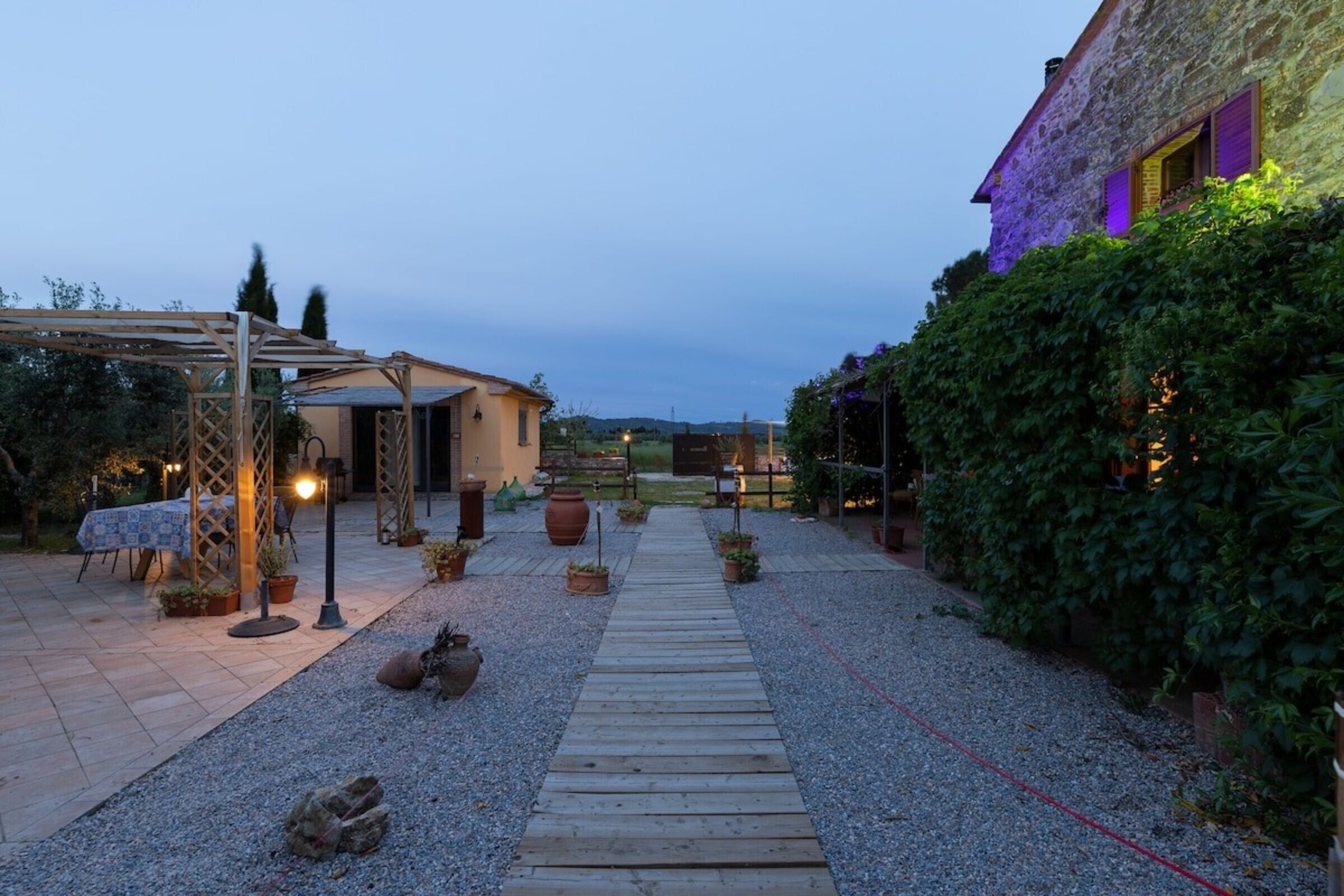 A courtyard with a wooden pathway, outdoor seating, and a pergola.