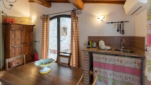 Una cocina rústica con una mesa de madera, un fregadero y una ventana con cortinas.