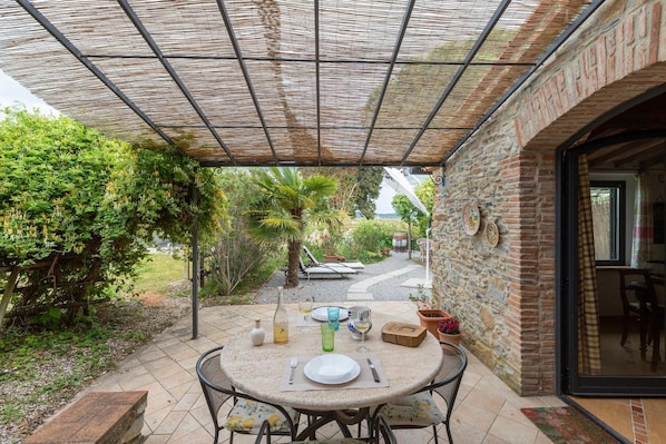 An outdoor patio with a round table, chairs, and a brick wall.