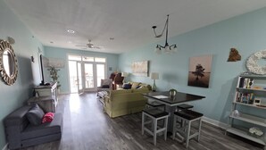 A spacious living area with a dining table, a sofa, and a bookshelf.