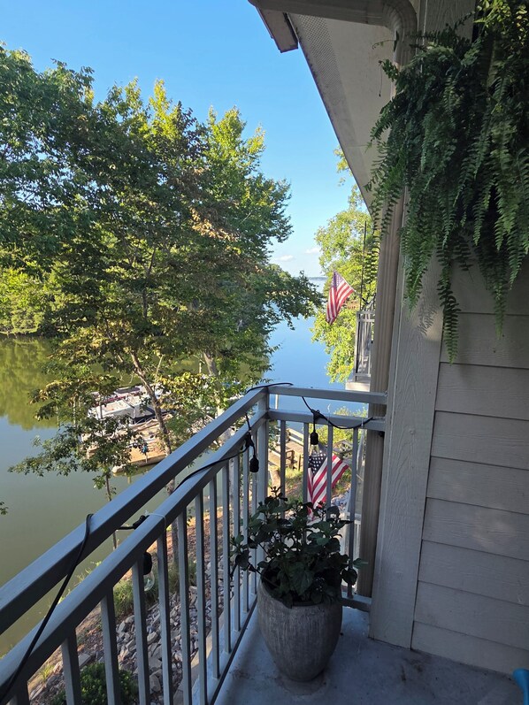 Een balkon met uitzicht op een meer, een bloempot en een Amerikaanse vlag.