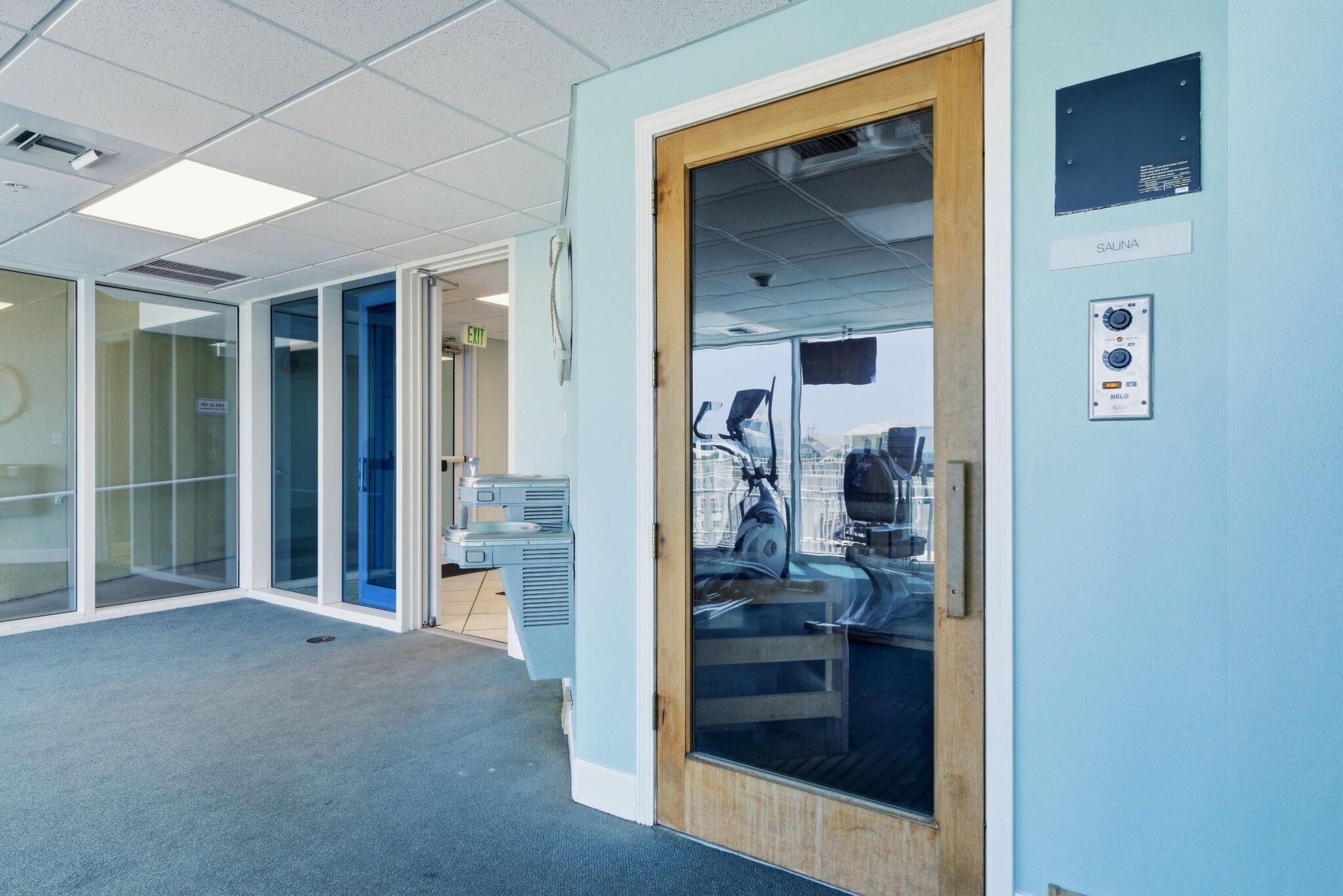 A modern office space with glass walls, a sauna, and a treadmill.