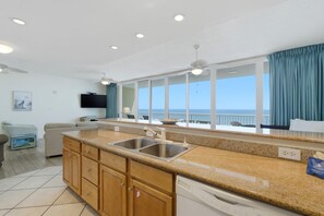 A kitchen with a large window, a ceiling fan, and a view of the ocean. - Sanibel 1204 (Gulf Shores)
