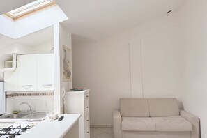 Eine moderne Küche mit Oberlichter, weißen Schränken und einem beigen Sofa in einem hellen Raum.