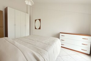 Una camera da letto con un letto, un armadio, una cassettiera e uno specchio.