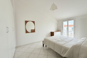 Ein Schlafzimmer mit einem Bett, einem Schminktisch, einem Spiegel und einem Fenster mit Blick.