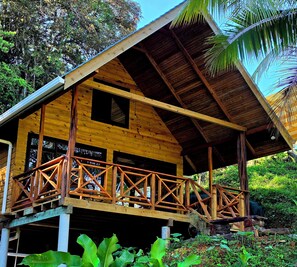 A wooden cabin with a balcony, surrounded by lush greenery. - Cabaña selva tranquila, autosostenible, The Pause. Para 4 huespedes maximo (Bocas del Toro)