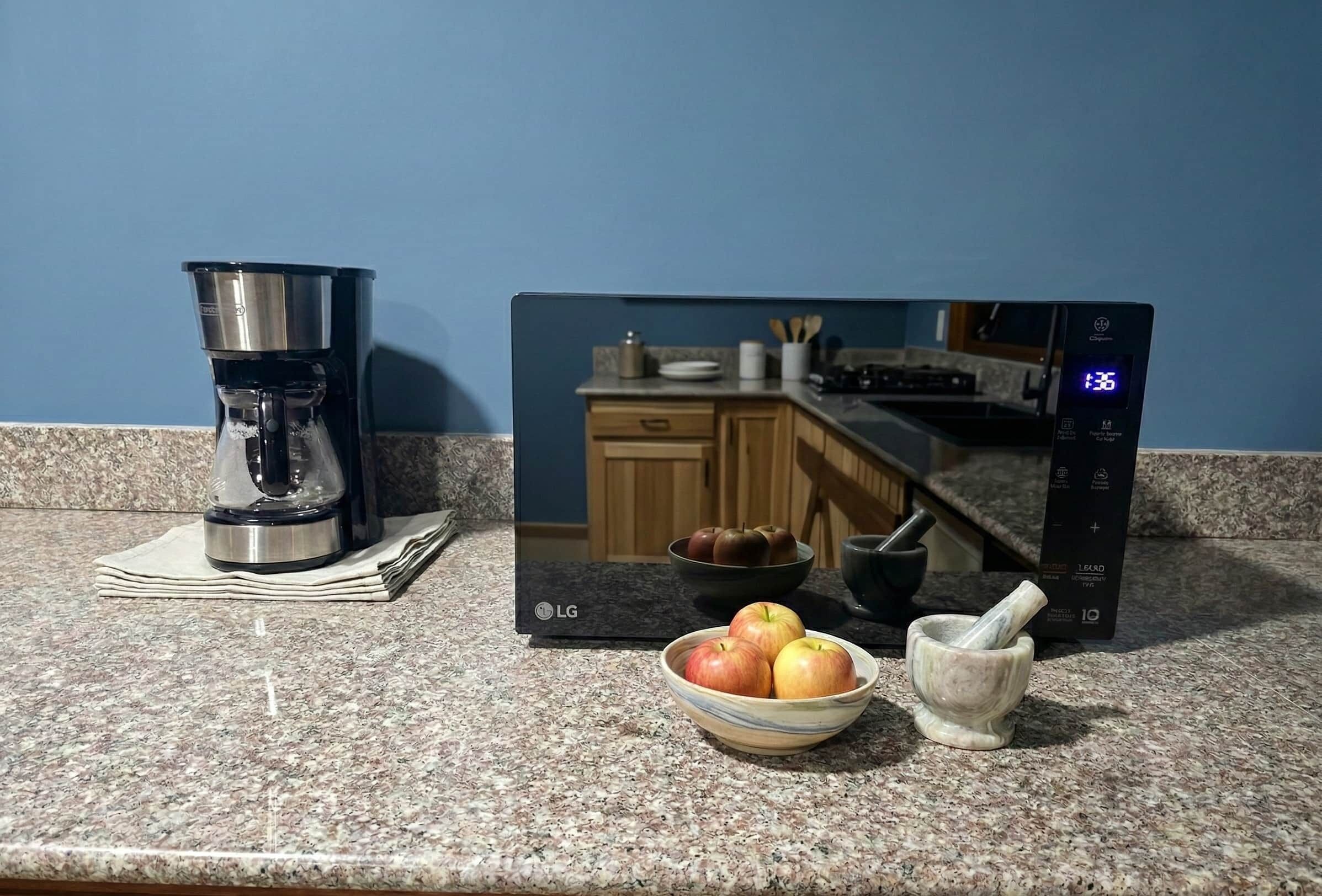 Eine Küchenarbeitsplatte mit Kaffeemaschine, einer Schüssel Äpfel und einem Mörser mit Stößel.