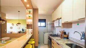 A modern kitchen with wooden cabinets, a built-in microwave, and a gas stove. - Apt in Condo w/ Pool 750 m Beach Rdw0103 (Camaçari)