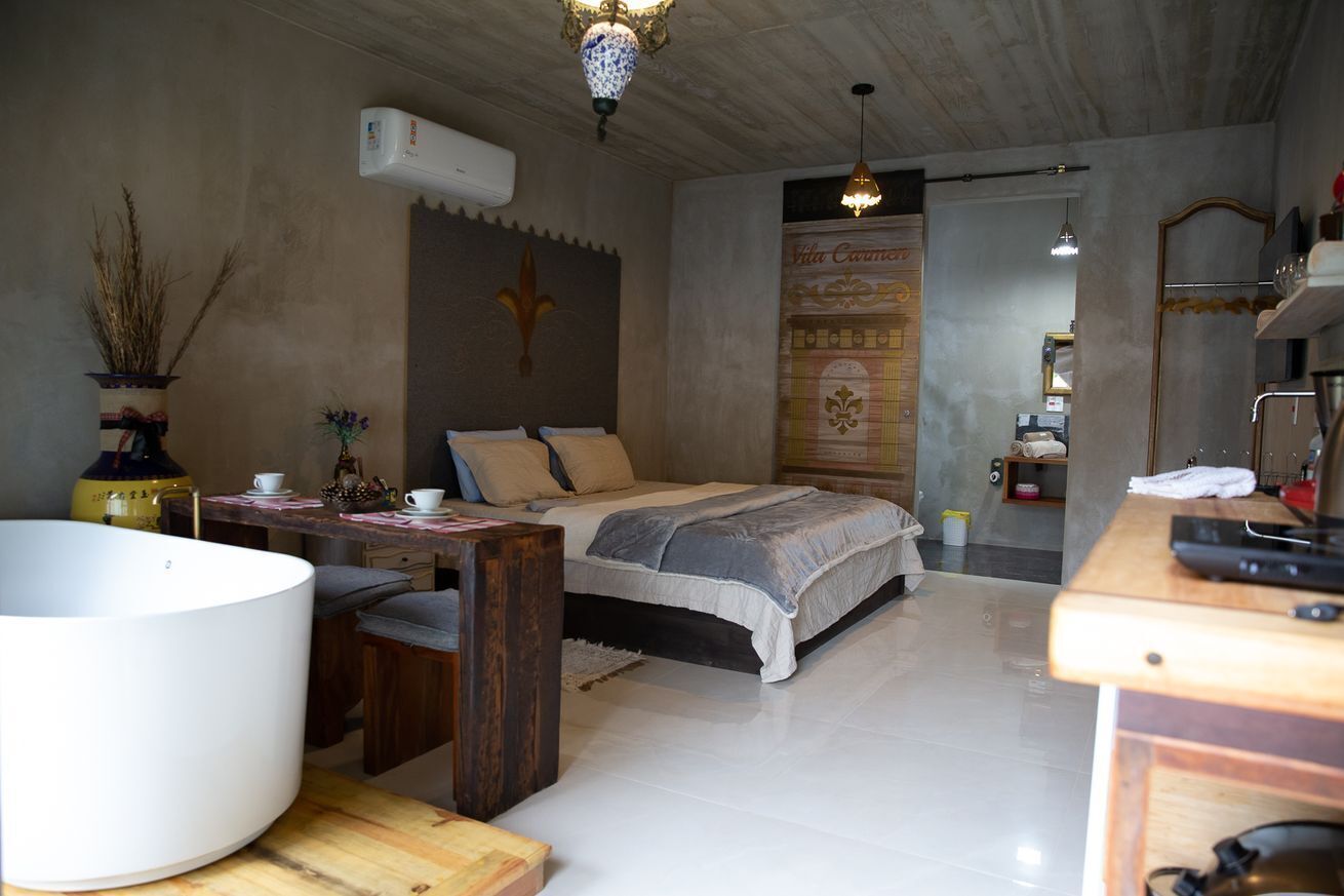 Quarto com cama, mesa de cabeceira e uma banheira branca grande.