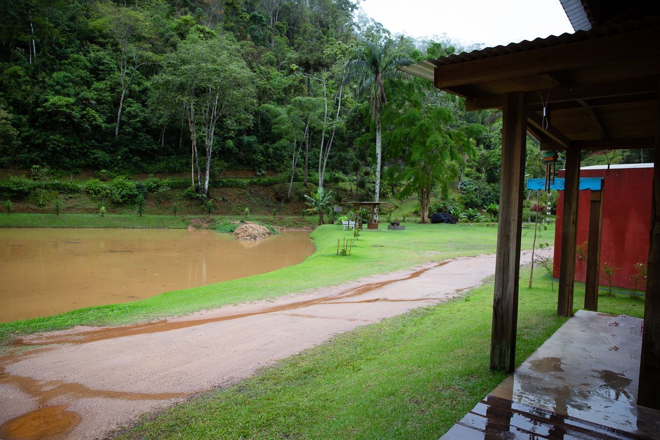 Uma área externa coberta com uma mesa de madeira e uma estrutura vermelha ao fundo.