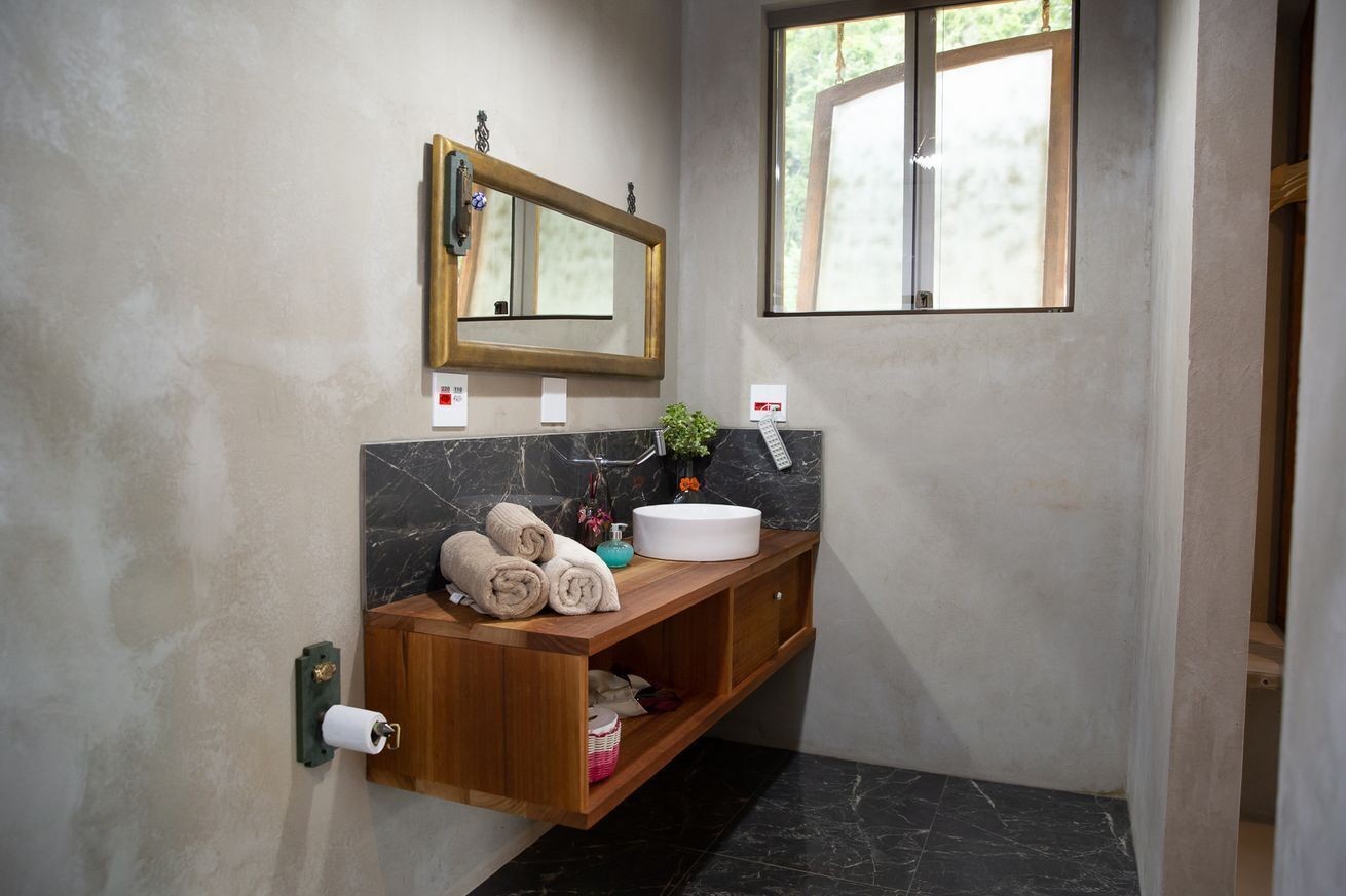 Une salle de bain avec un comptoir en marbre, un meuble-lavabo en bois, un miroir et une fenêtre.