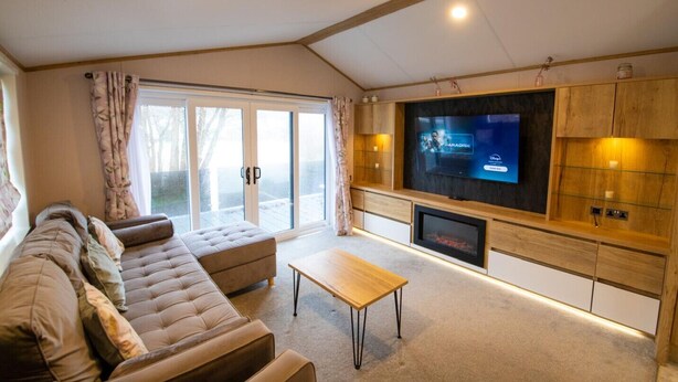 A living room with a large flat-screen TV, a sofa, a coffee table, and a fireplace.