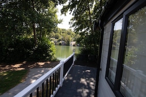 A deck with a railing overlooking a body of water and greenery.