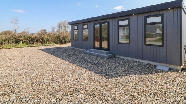A modern building with large windows and a gravel driveway.