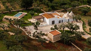 Vue aérienne d’une villa dotée d’une piscine, de murs en pierre et de toits coniques.