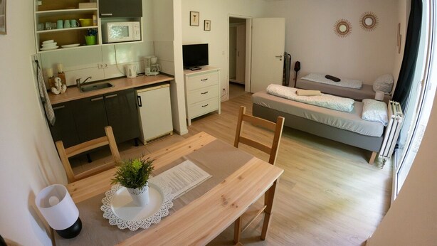 Ett kompakt bostadsutrymme med ett litet kök, en matplats och ett sovrum.