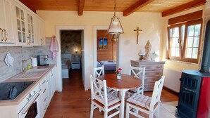 A kitchen with white cabinets, a wooden dining table, and a red stove.