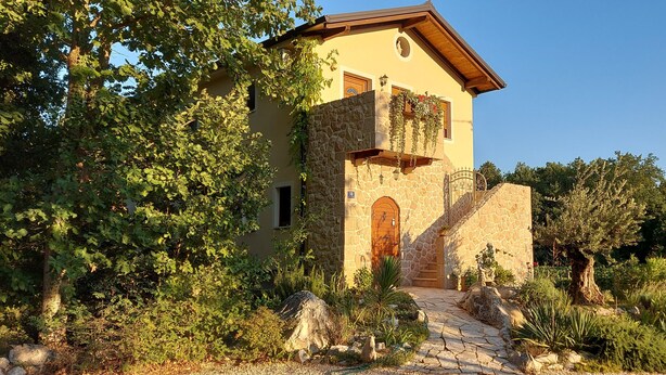 A stone building with a wooden door and a small balcony.