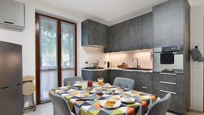 A modern kitchen with grey cabinets, a dining table with a colorful tablecloth, and a breakfast setting.