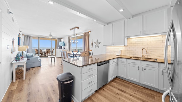A modern kitchen with white cabinets, a granite countertop, and a stainless steel refrigerator. - 🐠🌞Beachfront w/ Corner Balcony | Indoor + Outdoor Pools | Romar Place 506🌞🐠 (Orange Beach)