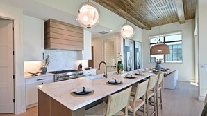 A modern kitchen with a large island, wooden ceiling, and pendant lighting. - Palmetto Sunset -Heat Pool/Spa, Steps to Beach! (Anna Maria)