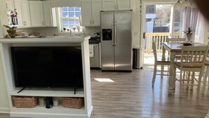 A modern kitchen with white cabinets, a stainless steel refrigerator, and a dining area with a wooden table and chairs. - Fun 3BR House in Rehoboth/Dewey Beach area (Rehoboth Beach)
