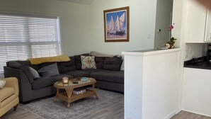 A living room with a sofa, a coffee table, and a kitchen area with cabinets. - Fun 3BR House in Rehoboth/Dewey Beach area (Rehoboth Beach)