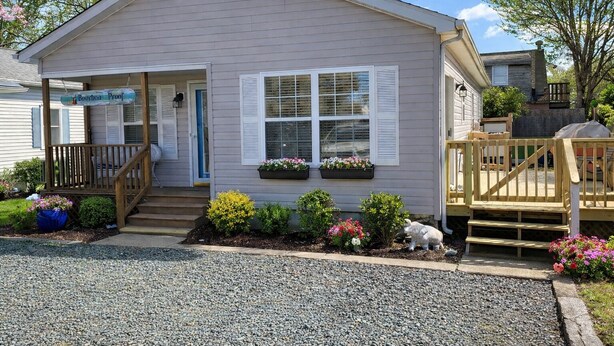 A single-story building with a porch, a small garden with flowers and shrubs, and a wooden deck. - Fun 3BR House in Rehoboth/Dewey Beach area (Rehoboth Beach)