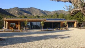 A modern building with a gravel driveway, solar panels, and a view of mountains.