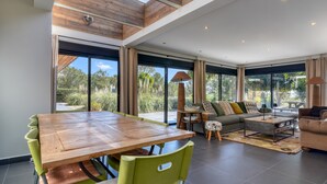 Een ruime woonkamer met een houten eettafel, groene stoelen, een bank en een salontafel.