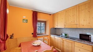 Uma cozinha compacta com armários de madeira, micro-ondas e janela com cortinas.