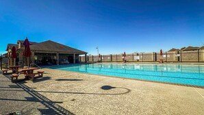 A swimming pool with a clear blue water, surrounded by a fence, and shaded by umbrellas. - Alpha Group - Room 1 (Richmond)
