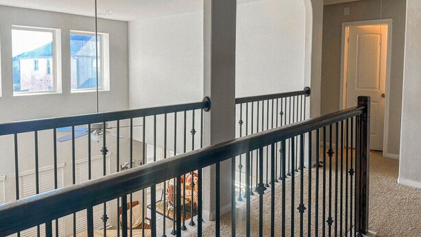 A spacious interior with a high ceiling, a staircase with a black railing, and a door leading to another room. - Alpha Group - Room 1 (Richmond)