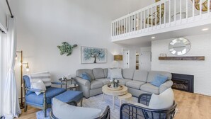 Een woonkamer met een zithoek, een salontafel en een open haard.
