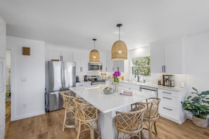 A modern kitchen with white cabinetry, stainless steel appliances, wicker pendant lights, and a central island with bar stools. - Villa Crystal/5bedrooms/Lakefront Luxury/Hot tub (Beulah)