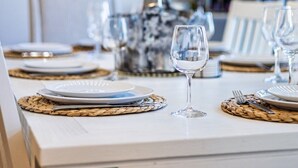 Een eettafel gedekt met borden, glazen en bestek, een geweven placemat en een hanglamp.