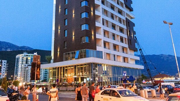 A multi-story hotel with a modern design, featuring a prominent glass facade and a series of balconies. - SeaLine Modern Studio in Budva Centar (Budva)