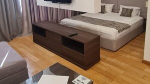 A modern hotel room with a large bed, a TV mounted on the wall, a wooden coffee table, and a sofa. - SeaLine Modern Studio in Budva Centar (Budva)