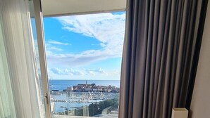 A hotel room with a bed, a view of a marina, and a balcony with curtains. - SeaLine Modern Studio in Budva Centar (Budva)