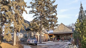 Une maison en pierre avec une façade en pierre, un porche couvert et une allée menant à un VUS garé.