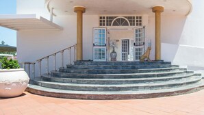 A building with a curved entrance, a set of stairs leading to a door with glass panels, and a statue of a dog. - Hotiday San Felice Circeo (San Felice Circeo)