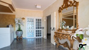 Un couloir orné d’un grand miroir, d’une plante en pot et d’une porte donnant sur une autre pièce.